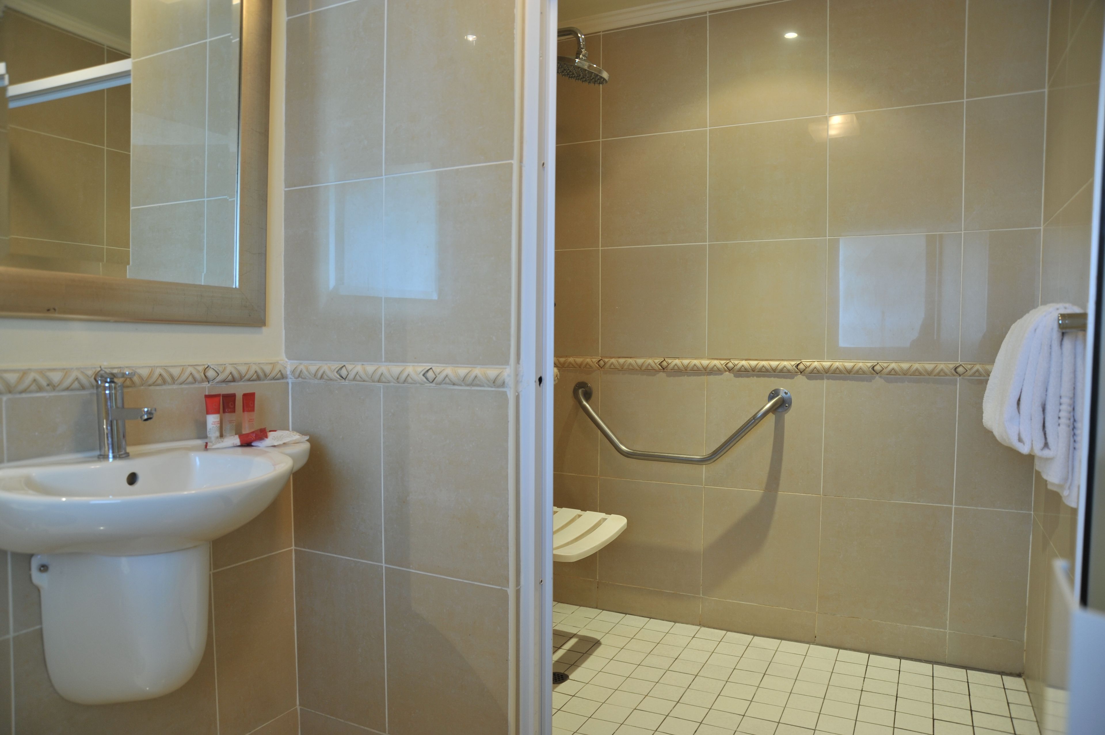 A bathroom with a sink, mirror, shower, and toilet.