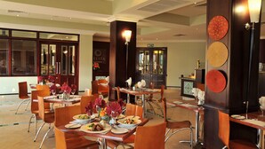 A restaurant with multiple tables, chairs, and a bar area. - Cresta President (Gaborone)