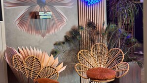 A room with a peacock feather wall art, a neon sign, and wicker chairs. - ibis Styles Paris Tolbiac Bibliotheque (Paris)