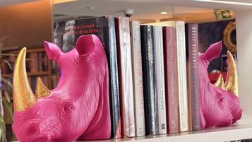 Une bibliothèque remplie de livres et ornée de deux sculptures de rhinocéros roses.