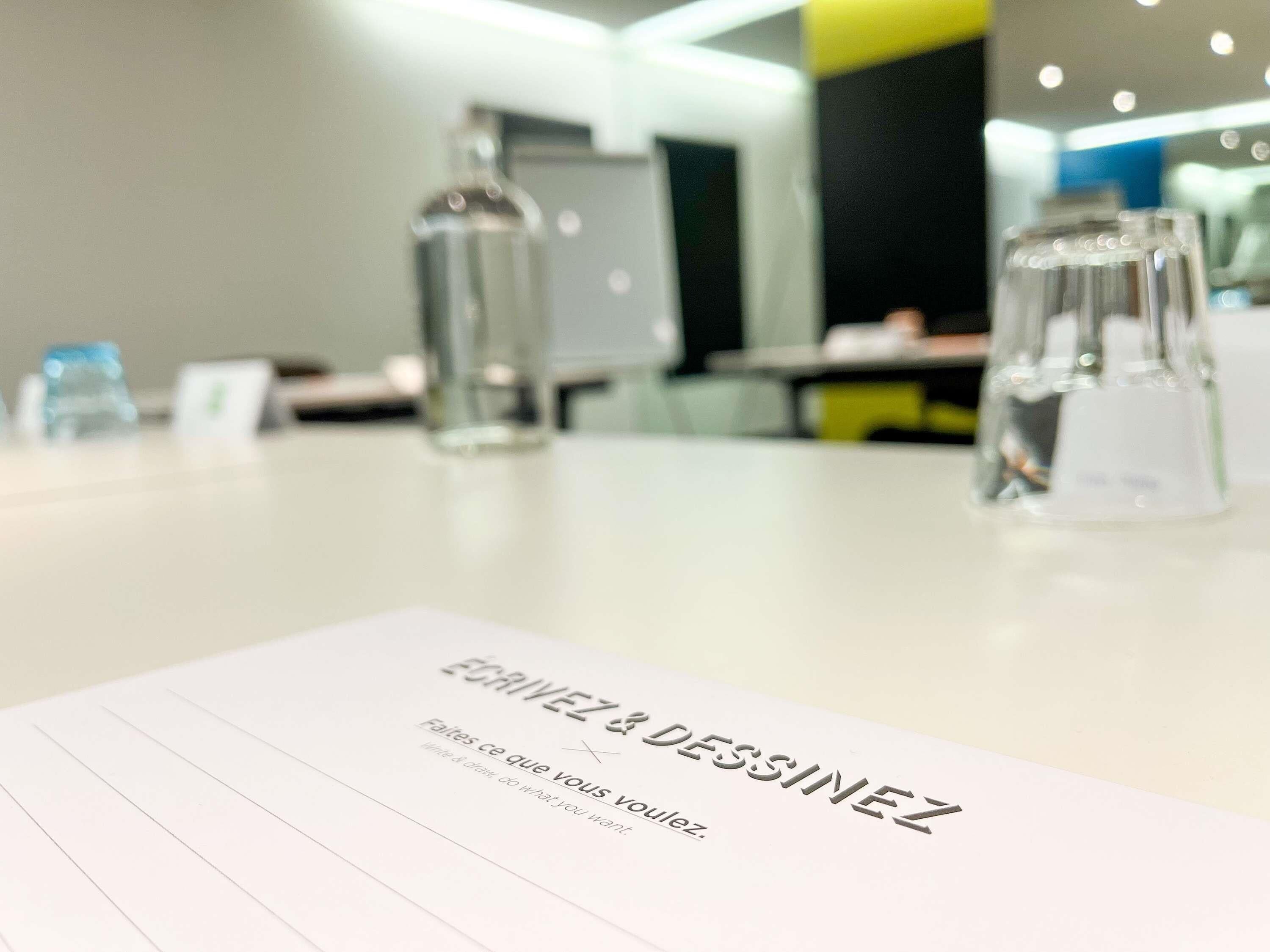 A table with a paper that reads 'EGRIVEZ & DESSINEZ' and 'Failes ce que vous voulez.'