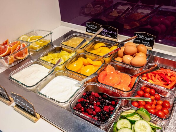 Un bufé con diversas opciones de comida, incluyendo frutas, verduras y huevos.