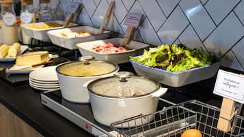A buffet with various food items, including a bowl of salad, a container of eggs, and several dishes with lids.