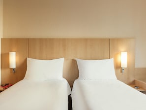 A hotel room with two beds, wooden headboard, nightstands, and wall-mounted lamps. - ibis Paris La Défense Esplanade (Courbevoie)