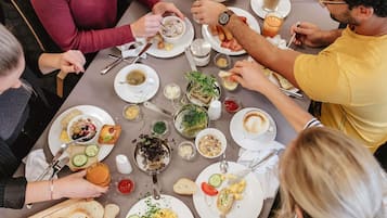 Un groupe de personnes est assis à une table et déguste différents plats, notamment des œufs brouillés et une soupe.