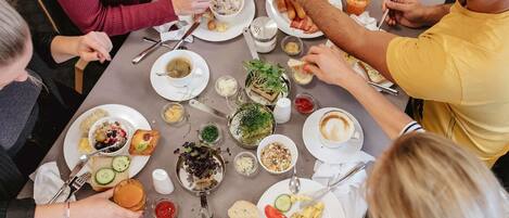 A group of people dining at a table with various dishes, including scrambled eggs and soup.