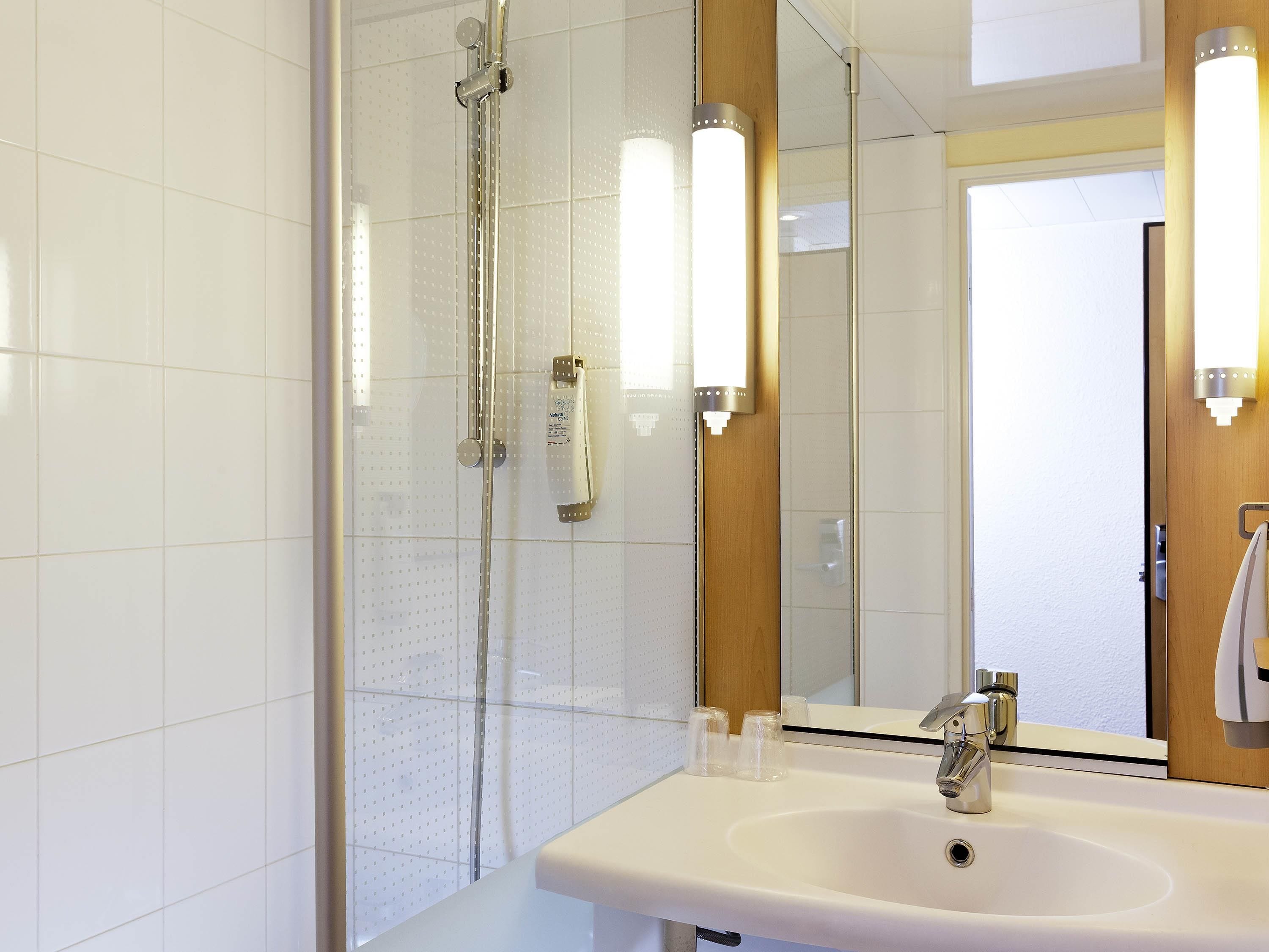 A modern bathroom with a shower, a sink, and a mirror.