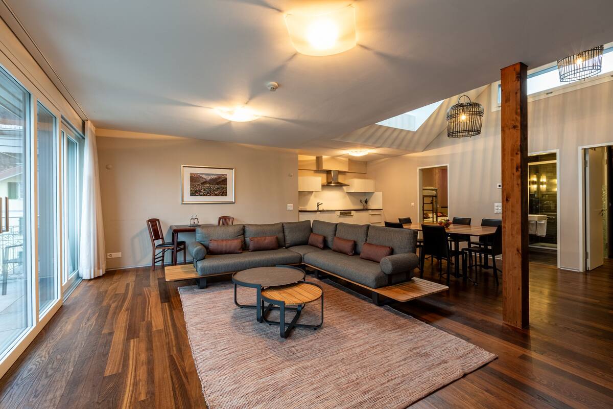 A modern living room with a sectional sofa, a round coffee table, and a dining area with a table and chairs.