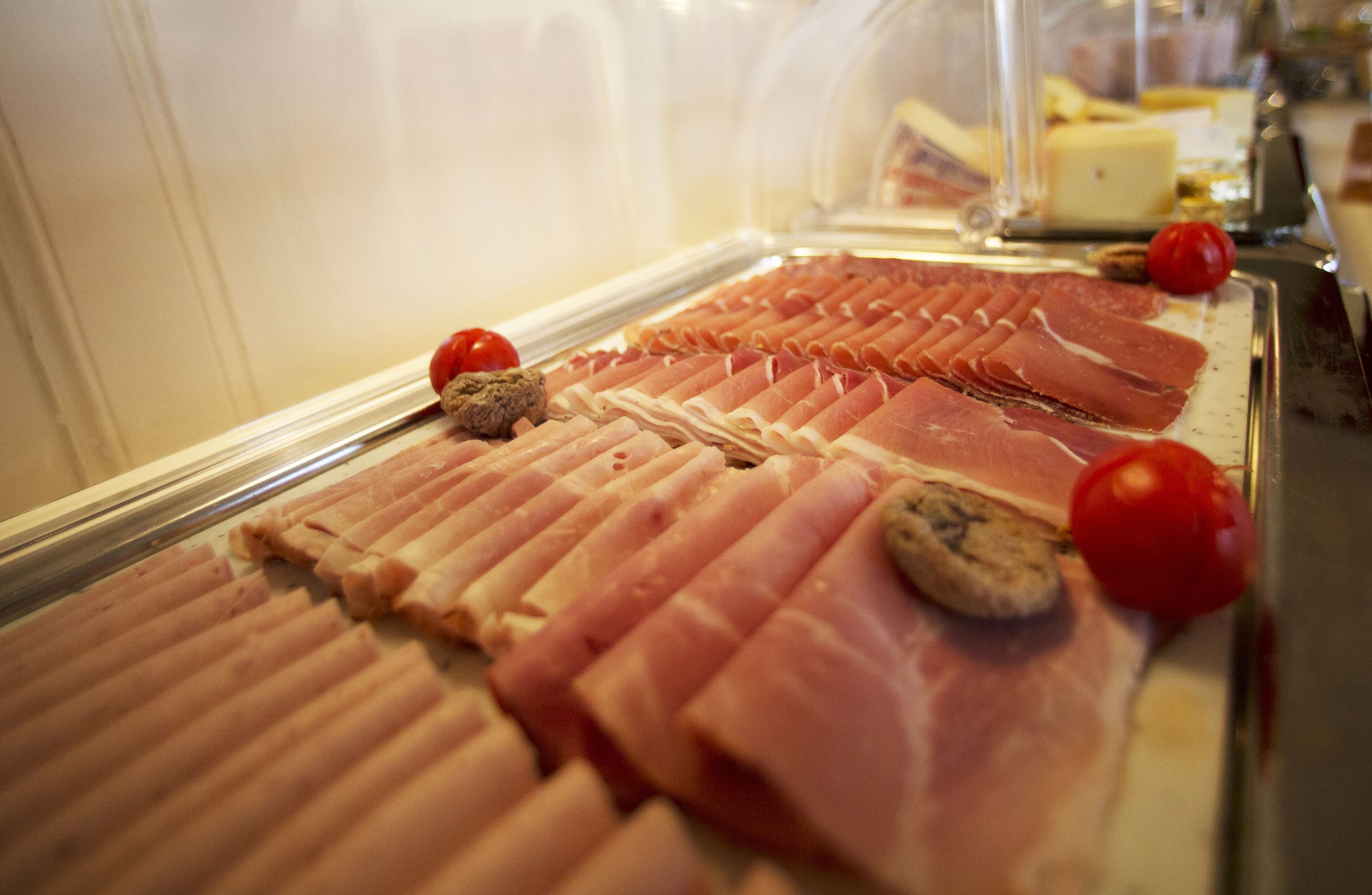 Une vitrine réfrigérée où sont exposées différentes sortes de charcuteries tranchées.