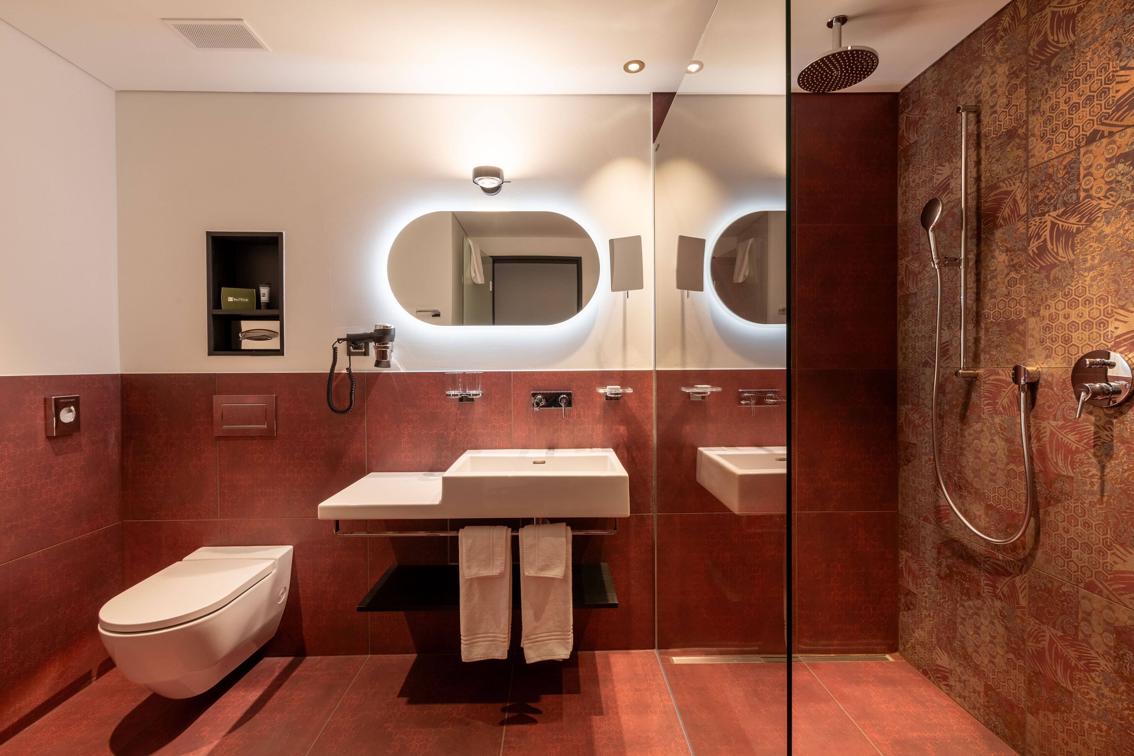 A modern bathroom with a large mirror, a white sink, and a shower area.