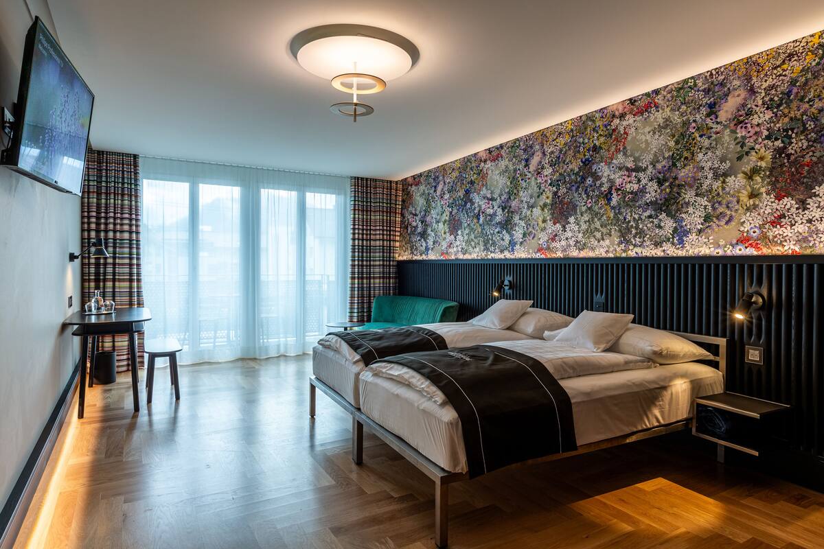 A modern hotel room with a large bed, a desk, and a television.