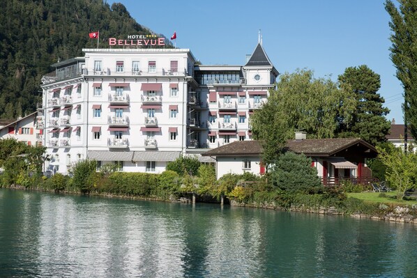 A multi-story hotel with balconies, a lake view, and a mountain backdrop. - Boutique Hotel Bellevue (Interlaken)