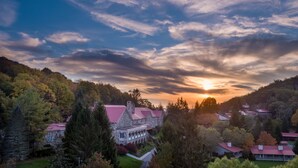 A large stone building with a red roof, surrounded by trees and hills. - Mountain Lake Lodge (Pembroke)