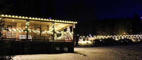 A snow-covered outdoor area with a building featuring a covered patio and string lights.