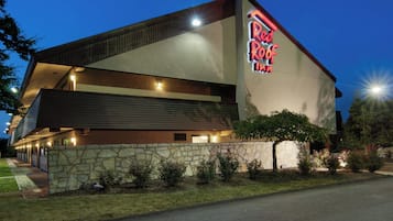 A Red Roof Inn with a stone facade, a flat roof, and a neon sign.