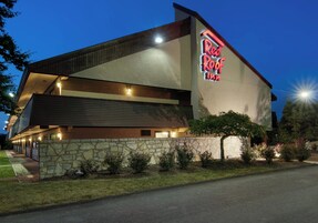Un Red Roof Inn con fachada de piedra, techo plano y letrero de neón.