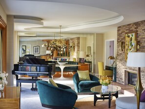 A spacious living room with a grand piano, comfortable seating, a glass coffee table, and a fireplace.
