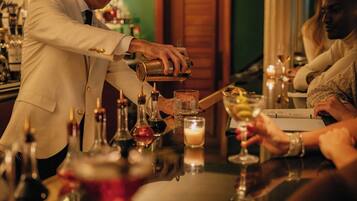 Un bar, un cantinero preparando una bebida, una vela en la mesa y un menú.