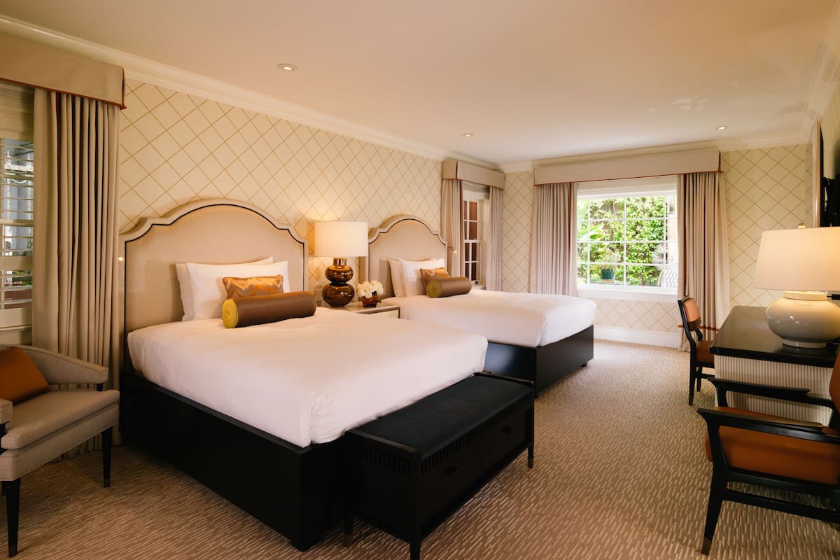 Ein Hotelzimmer mit zwei Betten, einem Schreibtisch und einem Stuhl.