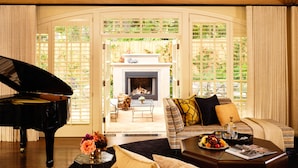 A luxurious living room with a grand piano, a cozy sofa, and a fireplace.