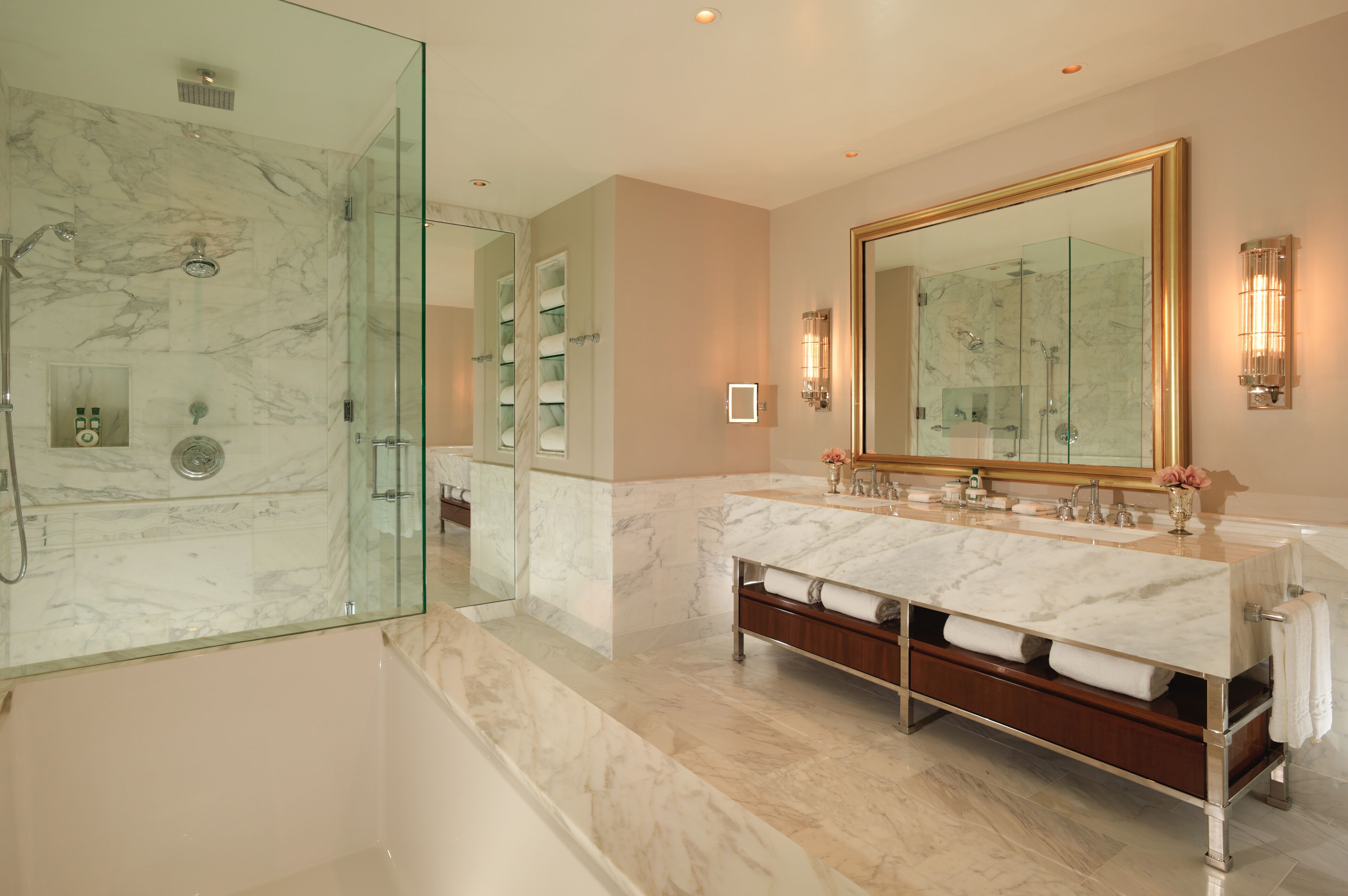 A modern bathroom with a glass-enclosed shower, a large mirror, and a marble vanity with dual sinks.