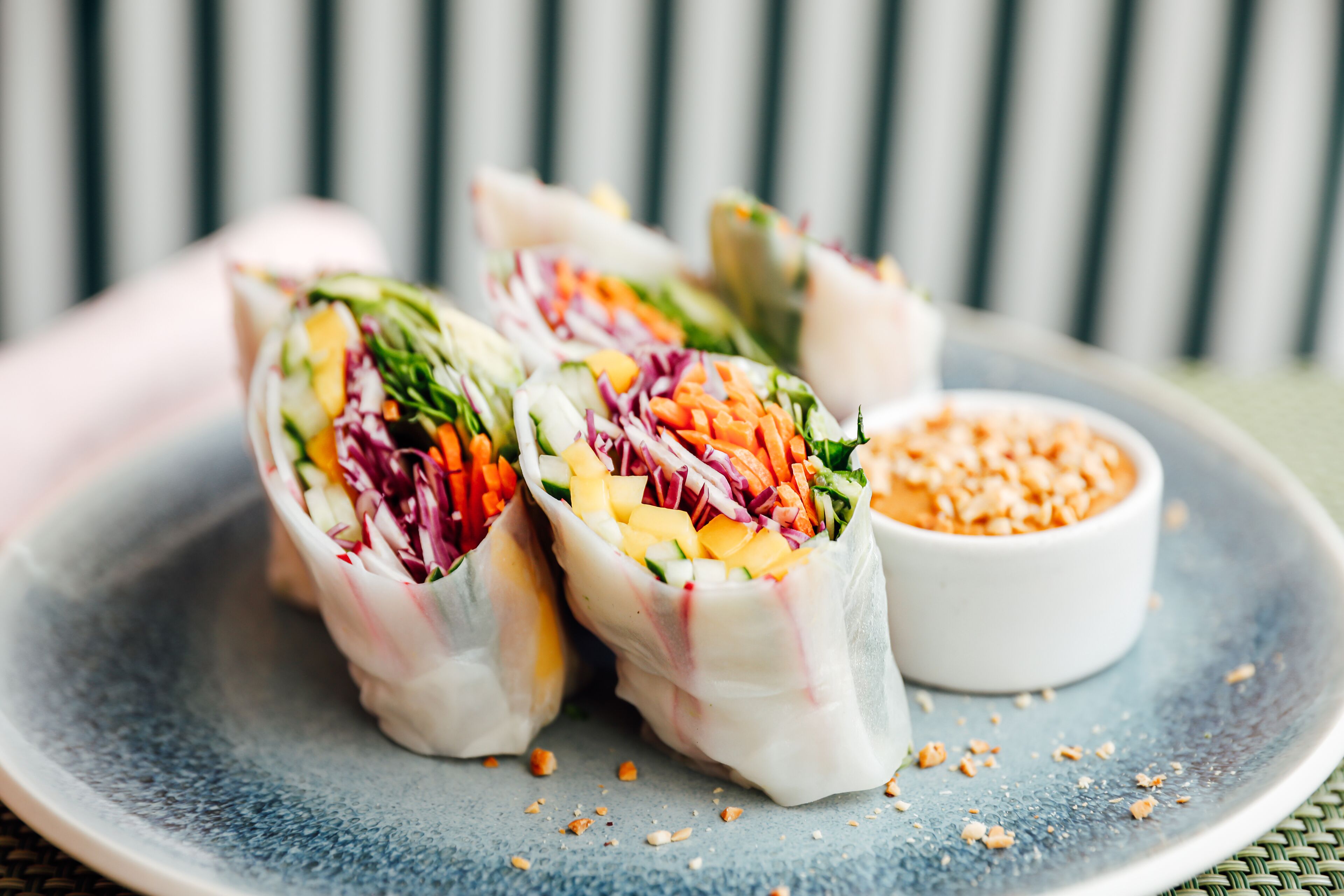 A plate with three spring rolls and a small bowl of sauce.