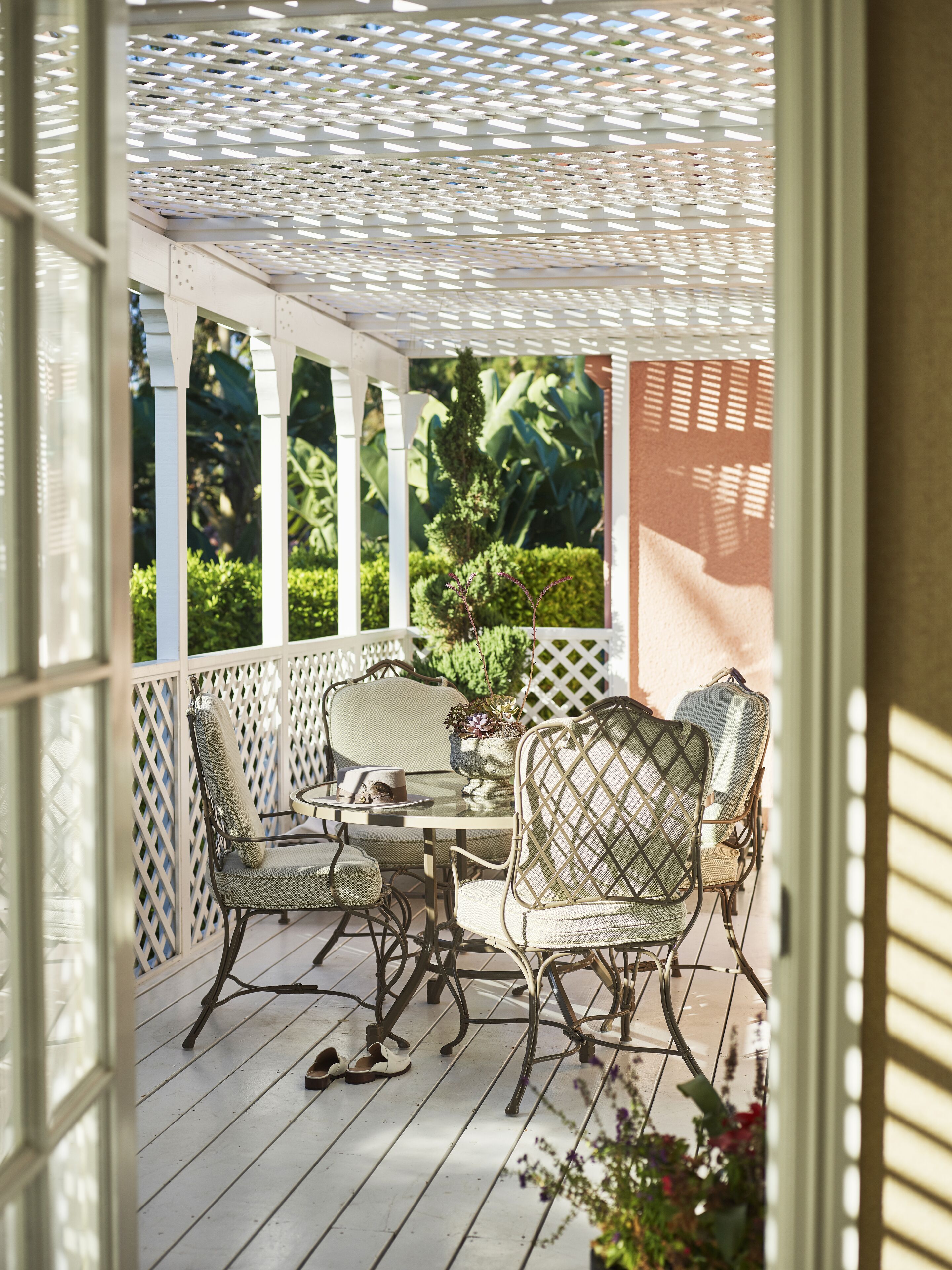 A covered patio area with a table and chairs, surrounded by a white lattice structure.