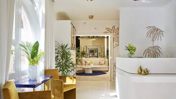 A modern living room with a sofa, chairs, a coffee table, and decorative plants.