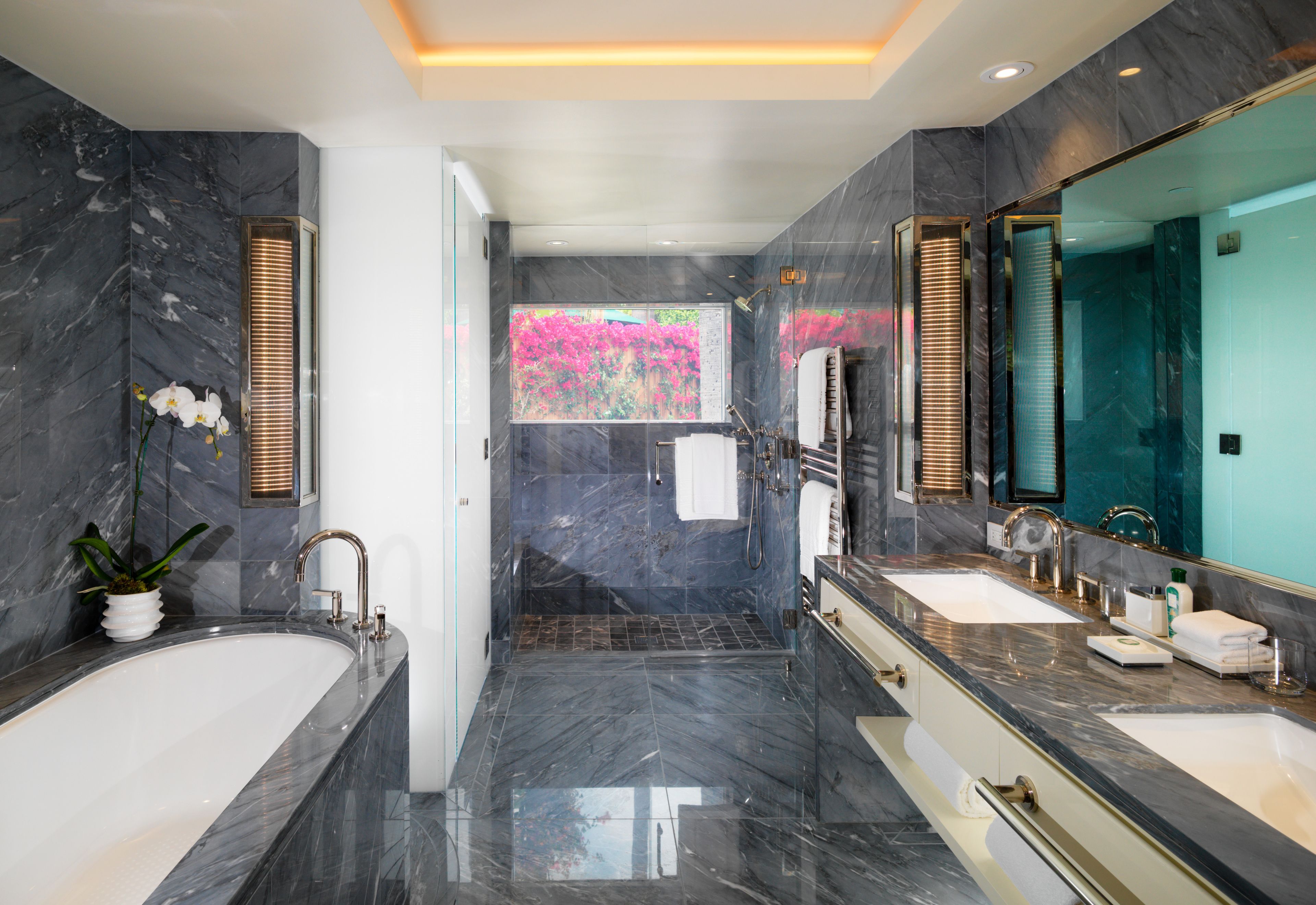 A modern bathroom with two sinks, a large bathtub, and a shower area.