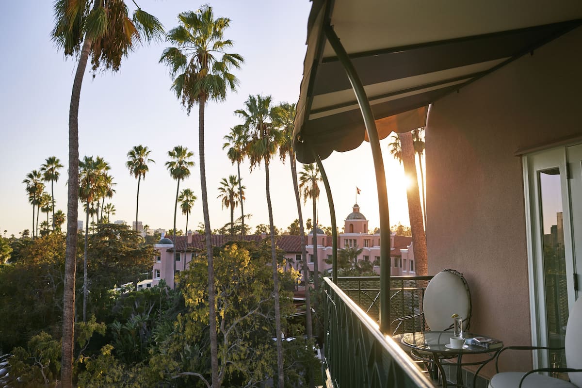 Ein Balkon mit Tisch und Stühlen, der Blick auf Palmen und ein Gebäude mit einer Kuppel bietet.