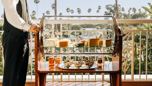 A waiter serving a variety of cheeses and pastries on a glass display case.
