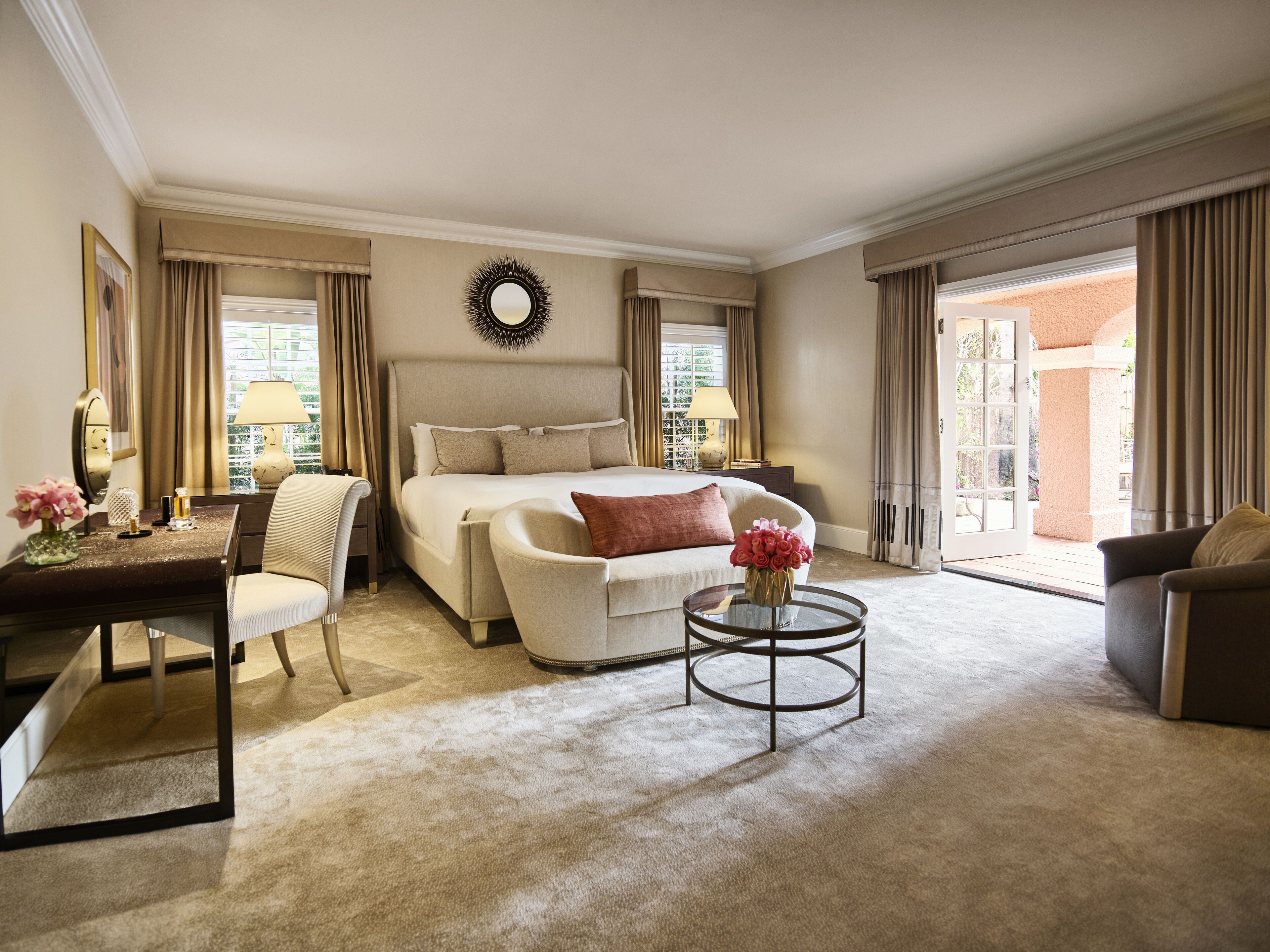 Ein geräumiges Hotelzimmer mit einem großen Bett, einer Sitzecke mit Couchtisch und einem Schreibtisch mit Lampe.