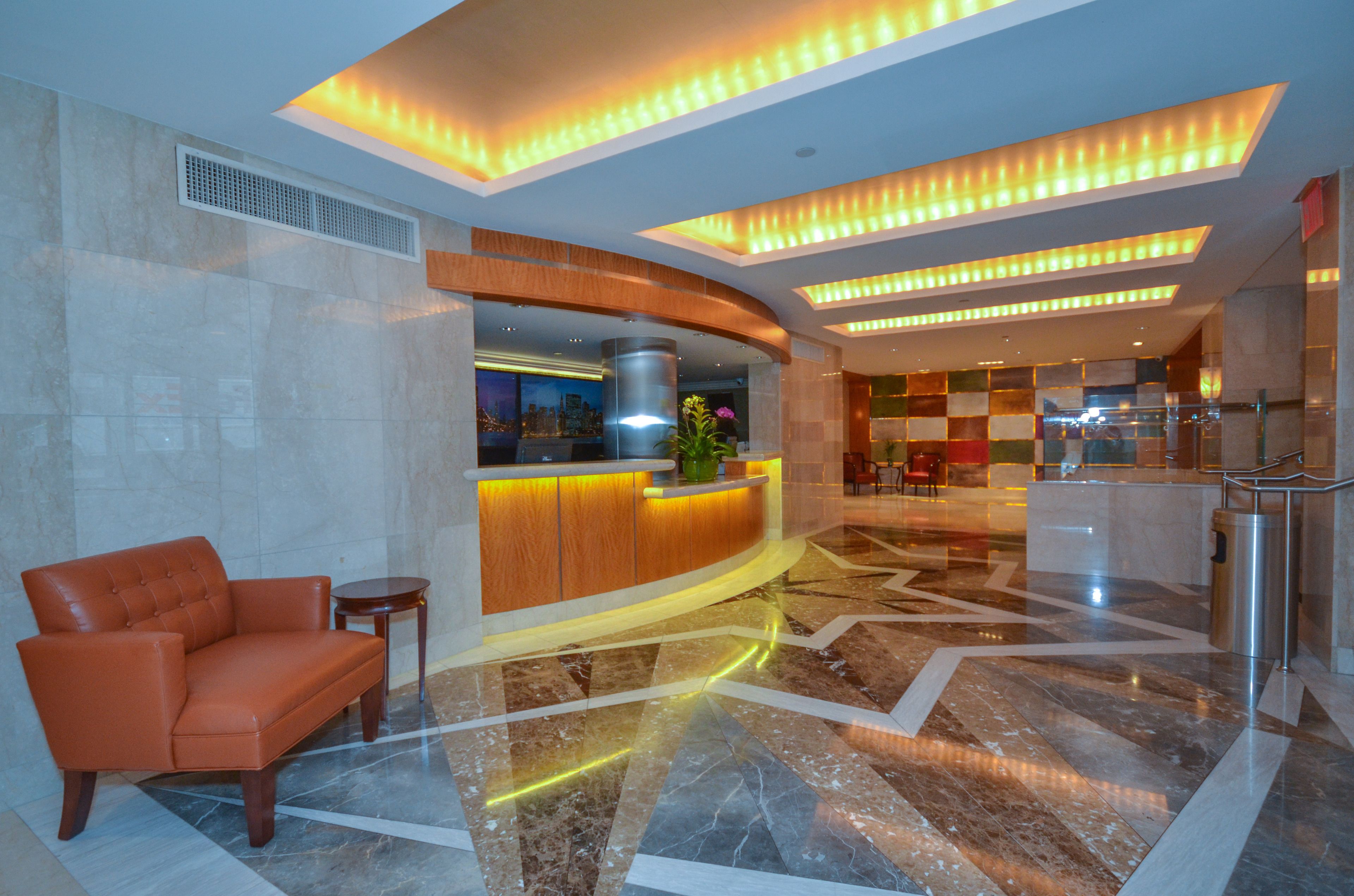 A lobby with a reception desk, a seating area, and a modern design with a marble floor and ceiling lights.