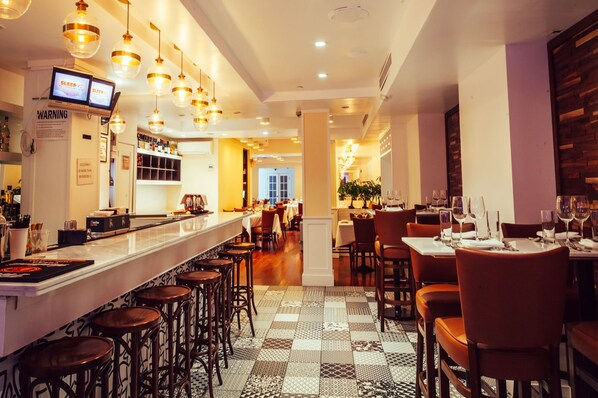 A restaurant interior with a bar area, multiple tables, and chairs. - San Carlos Hotel (New York)