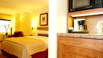 A hotel room with a bed, a desk, a microwave, and a coffee maker.
