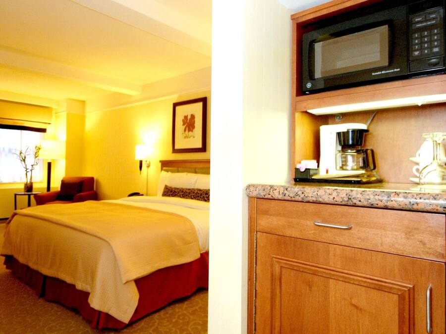 A hotel room with a bed, a desk, a microwave, and a coffee maker.