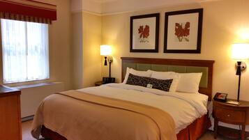 A hotel room with a large bed, two bedside lamps, a nightstand, and two framed floral pictures on the wall.