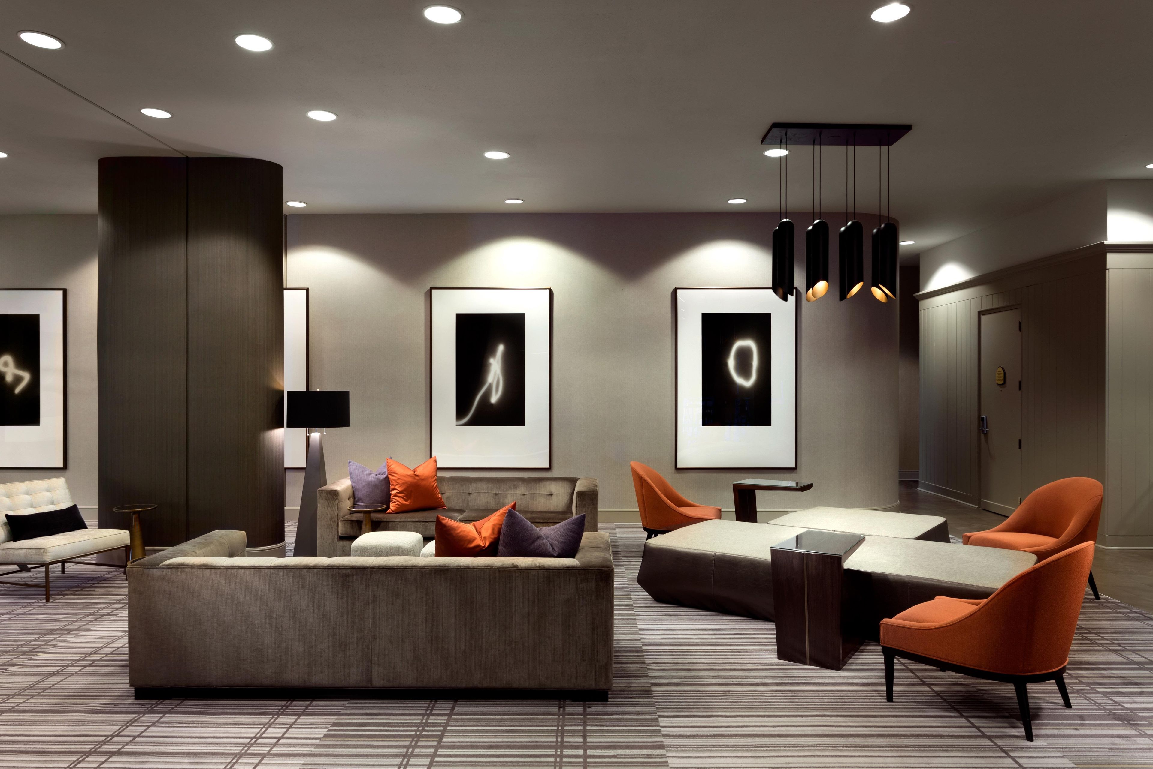 Een moderne hotellobby met een grote modulaire bank, fauteuils, een flatscreen-televisie en kunstwerken in lijsten aan de muren.