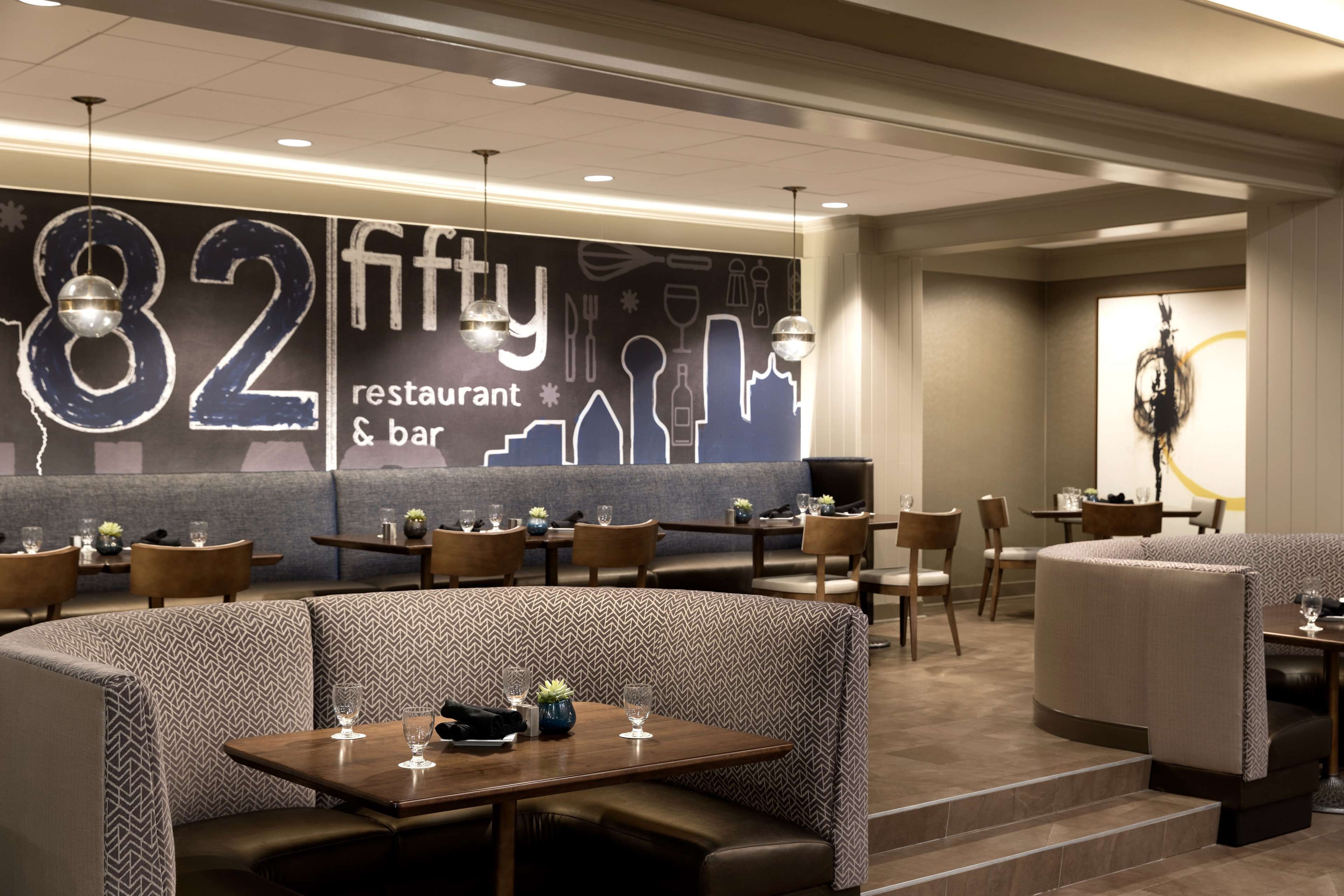 Restaurante com assentos em cabines, mesas e luminárias pendentes.