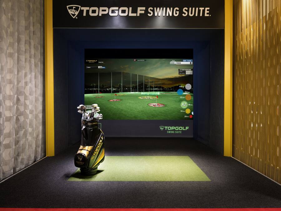 Configuración de simulación de golf con una pantalla TopGolf Swing Suite y un palo de golf.