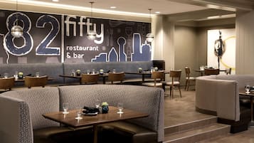 A restaurant interior with booth seating, tables, and a wall with a number '82' and 'fifty' text.