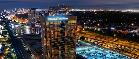 A high-rise hotel with a prominent sign, surrounded by a busy highway and city lights.