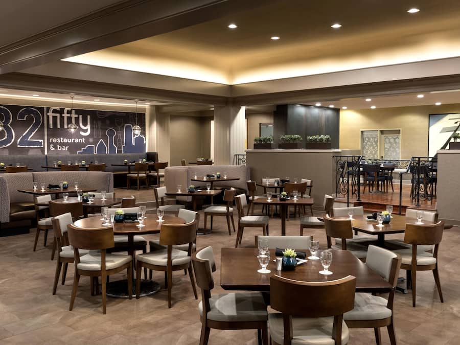 A restaurant interior with multiple dining tables and booths, a bar area, and a large wall with a 'fifty' sign.
