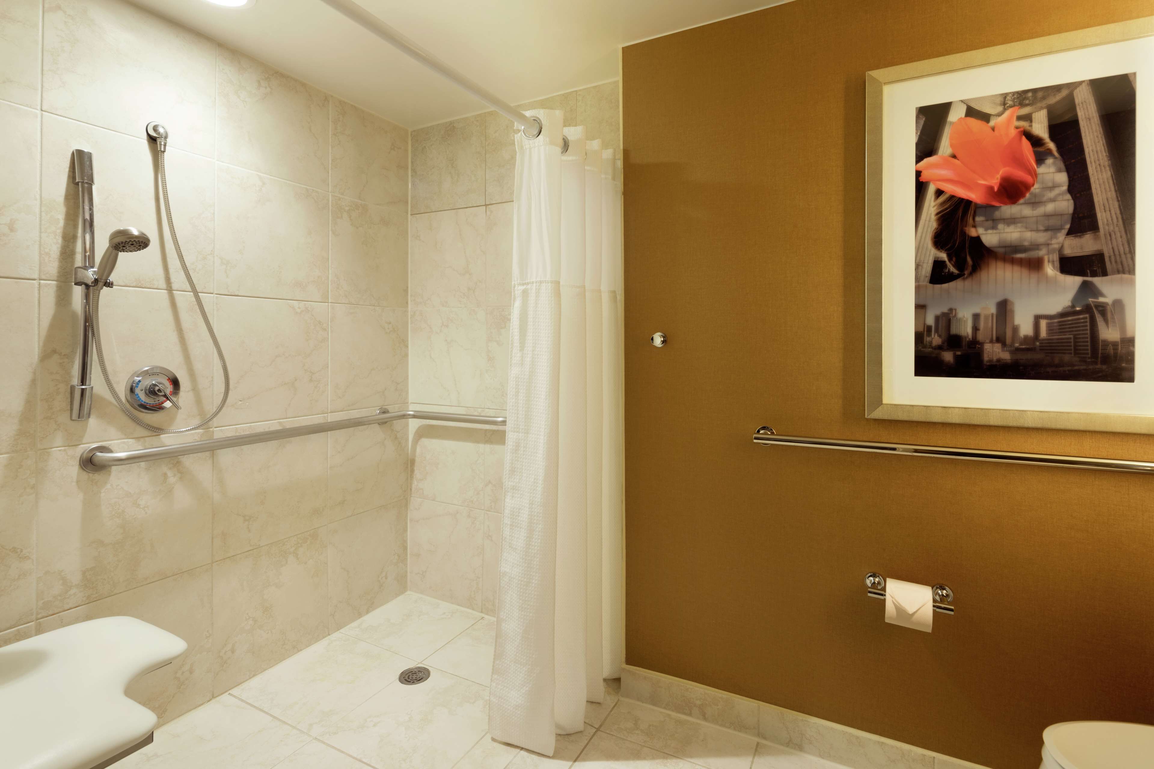 Un baño con ducha, inodoro y un cuadro en la pared.
