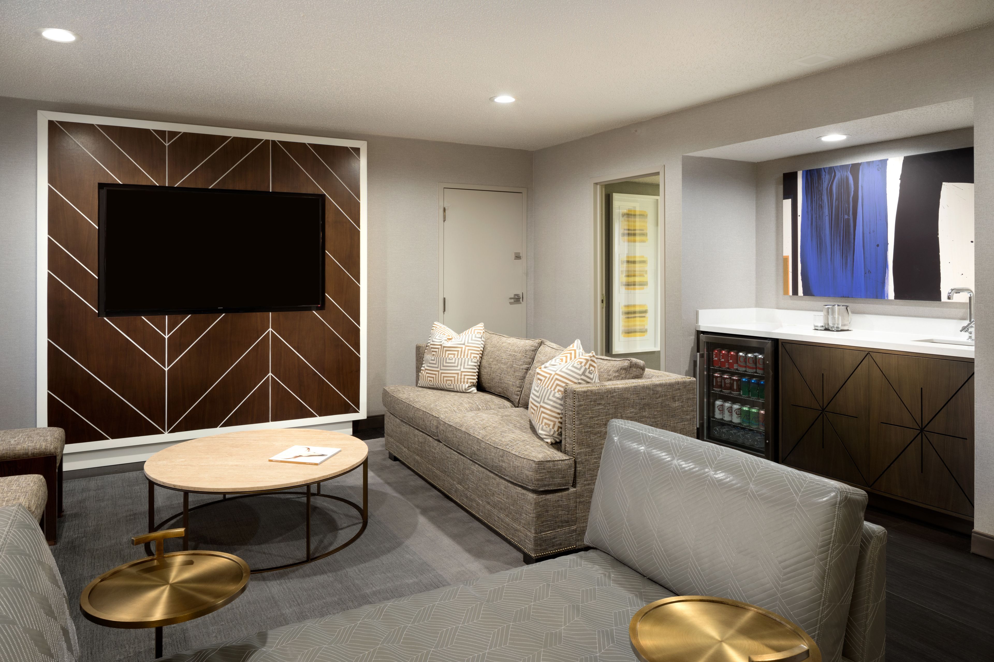 A modern living room with a sofa, a coffee table, and a flat-screen TV mounted on a wooden wall.