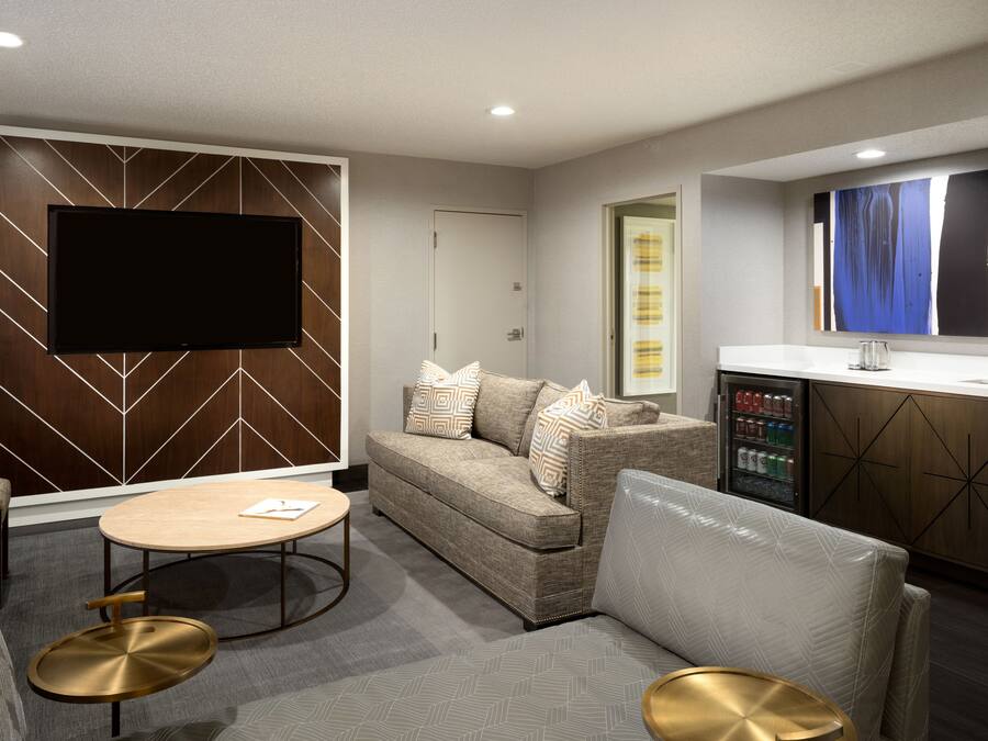 Una sala de estar moderna con un sofá, una mesita de centro y un televisor de pantalla plana montado en una pared de madera.