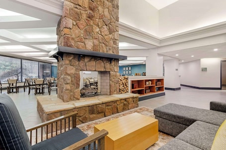 A spacious lobby with a stone fireplace, comfortable seating, and a view through large windows.