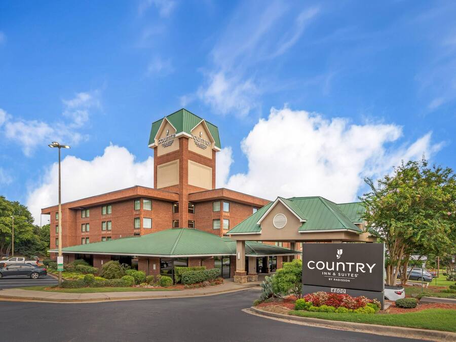A Country Inn & Suites hotel with a prominent tower, green roofing, and a landscaped entrance.