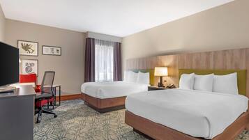 A hotel room with two beds, a desk with a computer, a chair, and a TV.