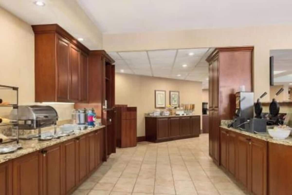A hotel kitchen with wooden cabinets, a buffet counter, and a tiled floor.